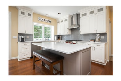 Example of a large classic l-shaped medium tone wood floor and brown floor eat-in kitchen design in Orange County with a drop-in sink, shaker cabinets, white cabinets, quartz countertops, blue backsplash, glass tile backsplash, stainless steel appliances, an island and white countertops