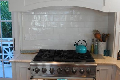 Enclosed kitchen - mid-sized traditional l-shaped medium tone wood floor and brown floor enclosed kitchen idea in Miami with recessed-panel cabinets, white cabinets, quartz countertops, white backsplash, subway tile backsplash, stainless steel appliances and no island