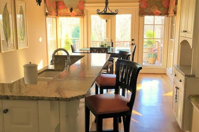 Inspiration for a large transitional l-shaped medium tone wood floor eat-in kitchen remodel in Other with an undermount sink, raised-panel cabinets, white cabinets, granite countertops and an island