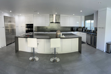 Example of an u-shaped kitchen design in Los Angeles with white cabinets, laminate countertops and an island