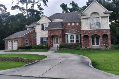 Large transitional two-story brick exterior home photo in Houston with a shingle roof and a gray roof