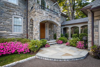 Large front yard partial sun garden in Philadelphia with with flowerbed and natural stone pavers for summer.