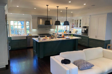 Large u-shaped dark wood floor, brown floor and coffered ceiling eat-in kitchen photo in Los Angeles with a farmhouse sink, recessed-panel cabinets, white cabinets, marble countertops, white backsplash, subway tile backsplash, stainless steel appliances, an island and white countertops