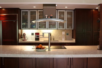 Kitchen - mid-sized contemporary galley kitchen idea in DC Metro with a farmhouse sink, flat-panel cabinets, dark wood cabinets, granite countertops, white backsplash, stainless steel appliances and an island