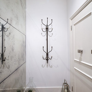 Immagine di un piccolo ingresso design con pareti con effetto metallico, parquet chiaro, una porta singola, una porta bianca e pavimento grigio