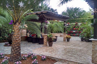 This is an example of a large backyard partial sun garden in Miami with a fire feature and natural stone pavers.