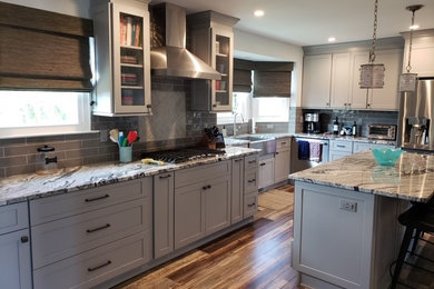 Eat-in kitchen - large modern l-shaped vinyl floor and multicolored floor eat-in kitchen idea in Philadelphia with a farmhouse sink, shaker cabinets, gray cabinets, granite countertops, gray backsplash, porcelain backsplash, stainless steel appliances and an island