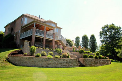 Photo of a mid-sized traditional partial sun backyard concrete paver retaining wall landscape in Other.