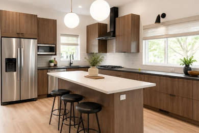 Example of a mid-sized kitchen design in Chicago with flat-panel cabinets, medium tone wood cabinets, white backsplash, an island and black countertops
