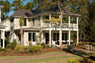 This is an example of a large traditional two-storey beige house exterior in Charleston with wood siding and a metal roof.