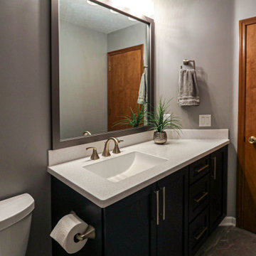 Guest Bathroom Dark Vanity with Corian Countertop and Tiled Wall above Tub