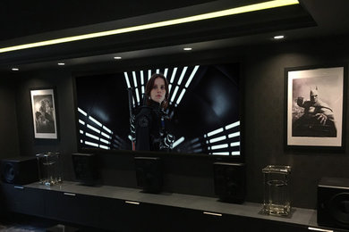 Ejemplo de cine en casa cerrado contemporáneo de tamaño medio con paredes negras, moqueta, pantalla de proyección y suelo gris