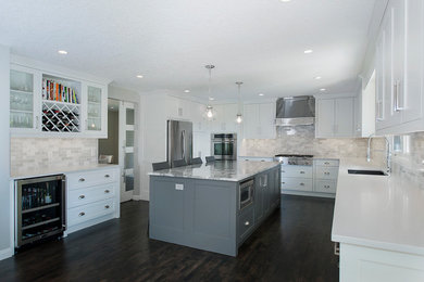 Photo of a large transitional l-shaped separate kitchen in Calgary with an undermount sink, shaker cabinets, white cabinets, solid surface benchtops, multi-coloured splashback, ceramic splashback, stainless steel appliances, dark hardwood floors and with island.