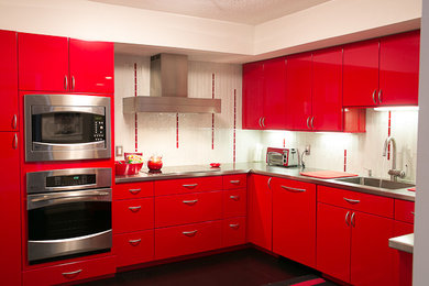 Design ideas for an eclectic l-shaped kitchen/diner in Dallas with a built-in sink, flat-panel cabinets, red cabinets, stainless steel worktops, white splashback, glass tiled splashback, stainless steel appliances, no island, black floors and grey worktops.