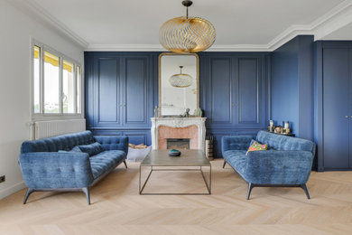 Idées déco pour un grand salon contemporain ouvert avec un mur bleu, parquet clair, une cheminée standard, un manteau de cheminée en pierre de parement, un téléviseur dissimulé et boiseries.
