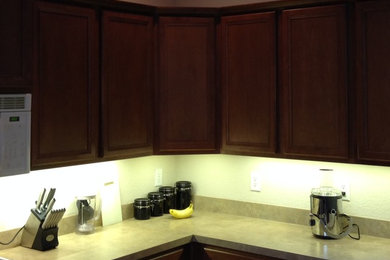 Eat-in kitchen - modern l-shaped eat-in kitchen idea in Dallas with a drop-in sink, recessed-panel cabinets, brown cabinets, granite countertops, white backsplash, stone tile backsplash and paneled appliances