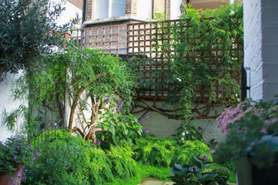 Small shabby-chic style back partial sun garden in London with a flowerbed and a wood fence.