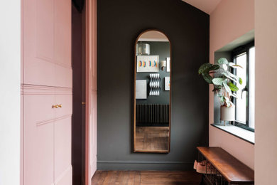 Photo of a contemporary boot room in London with pink walls, dark hardwood flooring, brown floors and a vaulted ceiling.