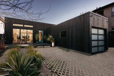 Ejemplo de fachada de casa negra minimalista de tamaño medio de una planta con revestimiento de madera y tejado plano
