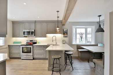 Example of a mid-sized country enclosed kitchen design in Toronto with a double-bowl sink, shaker cabinets, gray cabinets, white backsplash, stainless steel appliances and a peninsula