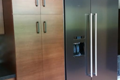 Example of a mid-sized transitional light wood floor and beige floor open concept kitchen design in Houston with flat-panel cabinets, medium tone wood cabinets, solid surface countertops, stainless steel appliances, no island, multicolored backsplash and glass tile backsplash