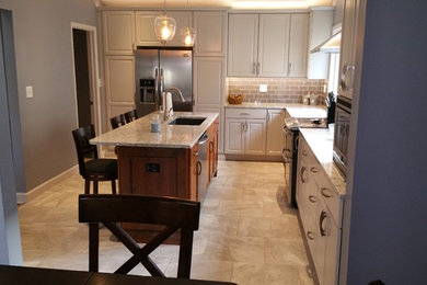 Example of a porcelain tile kitchen design in St Louis with an undermount sink, quartz countertops, gray backsplash, glass tile backsplash, stainless steel appliances and an island