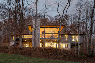 Inspiration for a large modern gray two-story wood house exterior remodel in Other with a hip roof, a metal roof and a gray roof