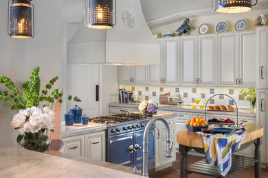 Example of a mid-sized classic terra-cotta tile kitchen design in Phoenix with a farmhouse sink, raised-panel cabinets, quartzite countertops, ceramic backsplash, colored appliances and an island