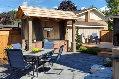 Photo of a mid-sized contemporary full sun concrete paver and wood fence landscaping in Other for summer.