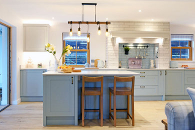Design ideas for a medium sized beach style galley open plan kitchen in Cornwall with shaker cabinets, blue cabinets, quartz worktops, metro tiled splashback, an island and white worktops.