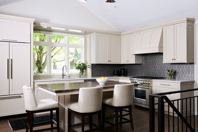Eat-in kitchen - mid-sized transitional l-shaped medium tone wood floor and brown floor eat-in kitchen idea in Minneapolis with an undermount sink, shaker cabinets, beige cabinets, granite countertops, beige backsplash, glass tile backsplash, stainless steel appliances, an island and multicolored countertops