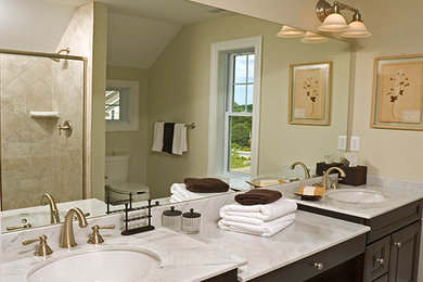 Mid-sized elegant master beige tile and ceramic tile bathroom photo in New York with an undermount sink, raised-panel cabinets, dark wood cabinets and marble countertops