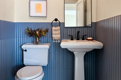 Example of a small island style blue tile and porcelain tile porcelain tile and gray floor powder room design in Los Angeles with gray cabinets, a two-piece toilet, beige walls and a pedestal sink