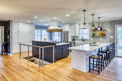 Inspiration for a large transitional u-shaped medium tone wood floor kitchen remodel in Other with white cabinets, quartz countertops, blue backsplash, ceramic backsplash, stainless steel appliances, an island and white countertops