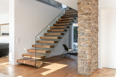 Ejemplo de escalera contemporánea con escalones de madera y barandilla de vidrio