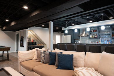 Example of a large classic underground vinyl floor, brown floor and exposed beam basement design in Detroit with a bar, gray walls and a hanging fireplace
