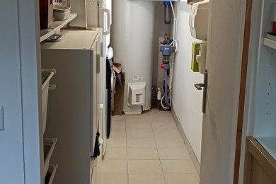 ボルドーにある低価格の中くらいなトラディショナルスタイルのおしゃれな家事室 (I型、白い壁、セラミックタイルの床、上下配置の洗濯機・乾燥機、ベージュの床) の写真
