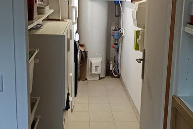 Idée de décoration pour une buanderie linéaire tradition multi-usage et de taille moyenne avec un mur blanc, un sol en carrelage de céramique, des machines superposées et un sol beige.
