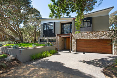 Mid-sized contemporary two-storey grey house exterior in Melbourne with stone veneer, a gable roof and a metal roof.