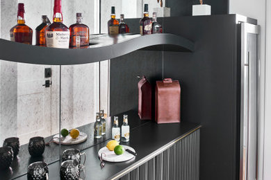 Example of a minimalist medium tone wood floor and black floor home bar design in Atlanta with no sink, floating shelves, black cabinets and mirror backsplash