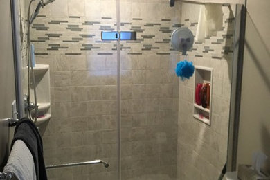 Example of a small transitional 3/4 alcove shower design in Baltimore with black cabinets, a one-piece toilet, brown walls, an undermount sink, solid surface countertops, a hinged shower door and white countertops