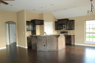 Mid-sized elegant l-shaped dark wood floor open concept kitchen photo in Other with an undermount sink, beaded inset cabinets, dark wood cabinets, granite countertops, brown backsplash, ceramic backsplash, stainless steel appliances and an island