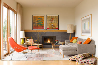 Design ideas for a midcentury open concept living room in Seattle with light hardwood floors, a tile fireplace surround, a standard fireplace, no tv and beige walls.