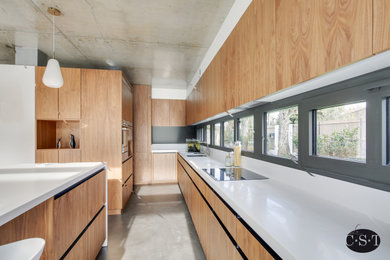 Inspiration pour une grande cuisine américaine encastrable design en L et bois brun avec un évier encastré, un placard à porte affleurante, un plan de travail en surface solide, une crédence blanche, sol en béton ciré, îlot, un sol gris et un plan de travail blanc.