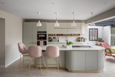 Inspiration for a medium sized contemporary open plan kitchen in Cambridgeshire with an integrated sink, flat-panel cabinets, white cabinets, composite countertops, white splashback, glass sheet splashback, black appliances, cork flooring, an island, beige floors and white worktops.