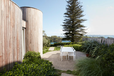 Inspiration for a modern partial sun garden in Sydney with gravel and a wood fence.
