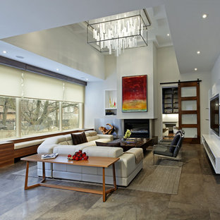 Modelo de salón abierto, actual, grande, con suelo de cemento, paredes blancas, chimenea tradicional, marco de chimenea de hormigón y pared multimedia