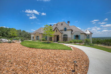 Inspiration for a large french country stucco exterior home remodel in Austin with a hip roof and a tile roof