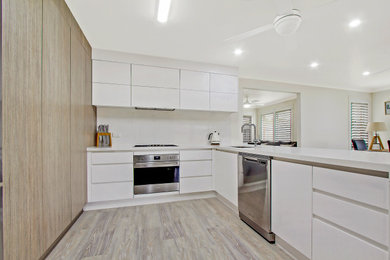 シドニーにある中くらいなモダンスタイルのおしゃれなダイニングキッチン (シングルシンク、フラットパネル扉のキャビネット、白いキャビネット、クオーツストーンカウンター、白いキッチンパネル、クオーツストーンのキッチンパネル、シルバーの調理設備、白いキッチンカウンター) の写真