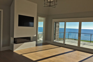 Example of a large trendy open concept light wood floor and brown floor living room design in Toronto with beige walls, a hanging fireplace, a concrete fireplace and a wall-mounted tv